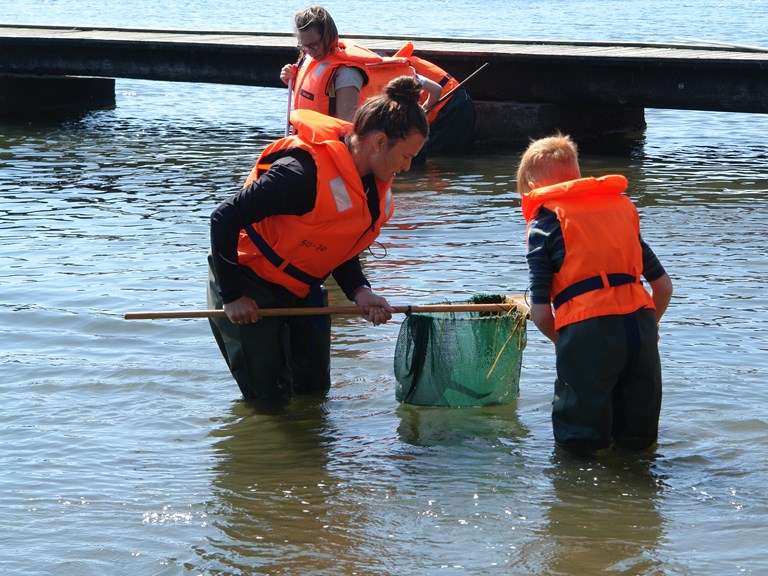 3 mennesker i waders med fiskenet i fjorden. 